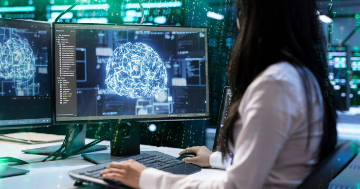 女性社員がAIが表示されているモニタに向かって作業をしている様子。内製開発のメリットとして、現場のニーズに即座に対応する姿勢を表現。