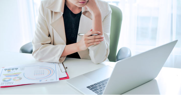 ペンを手に持ちPC画面を見るビジネスパーソンの姿を通して、RPA・AIで奉行クラウド入力を自動化し、作業負荷とミス削減を実現しているイメージ。